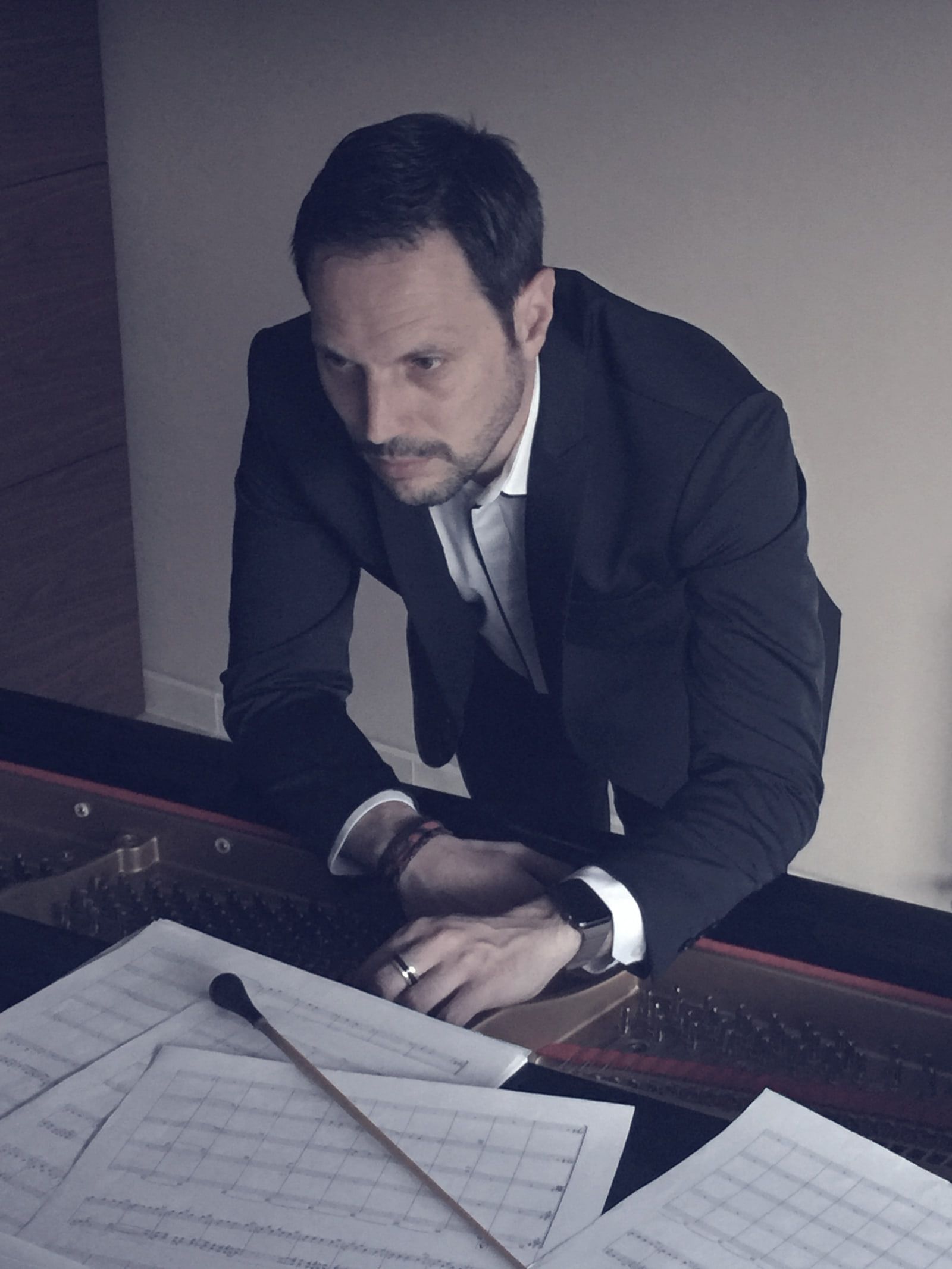 Sergio Cano Ortiz inclinado sobre partituras manuscritas extendidas encima del piano.